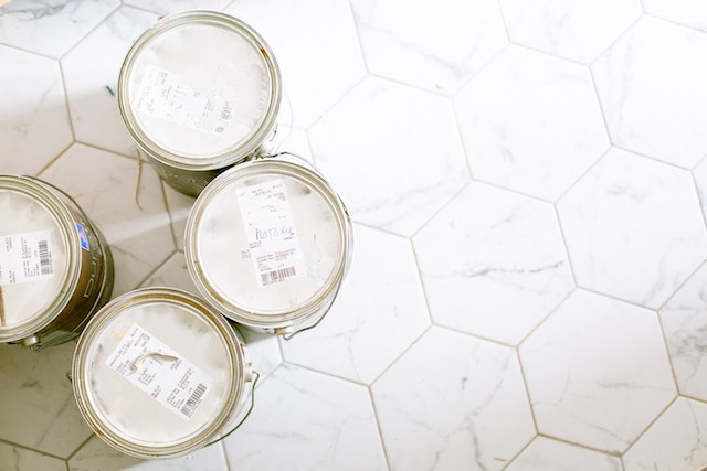 Four closed cans of paint on a marble floor